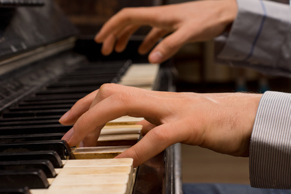 Male pianist playing music on an ivory keyboard